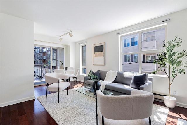 living room with track lighting, baseboards, baseboard heating, and dark wood-type flooring