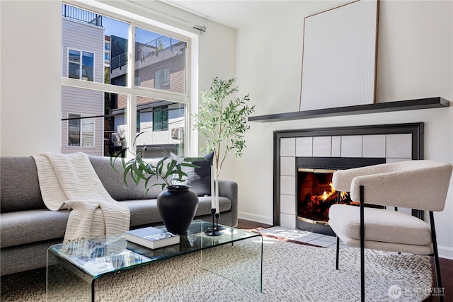 living area with a fireplace, baseboards, and wood finished floors