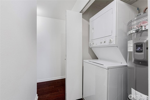 clothes washing area featuring dark wood-style floors, stacked washer / drying machine, laundry area, and baseboards