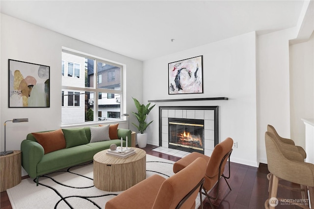 living area featuring a tile fireplace and dark wood finished floors