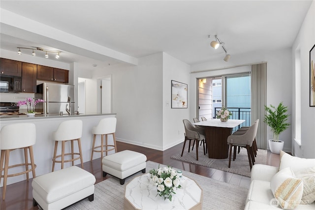 living room featuring baseboards, rail lighting, and light wood-style floors