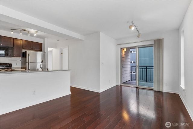 unfurnished living room with track lighting, dark wood-style flooring, and baseboards