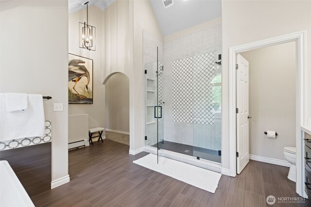 bathroom featuring a stall shower, toilet, lofted ceiling, baseboard heating, and vanity