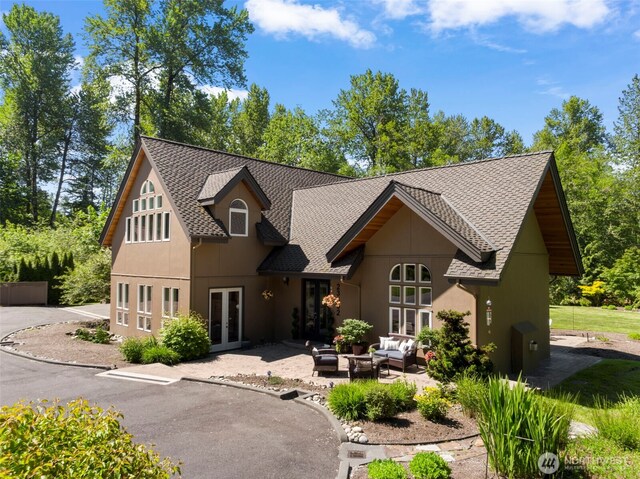 view of front of home with a patio area, a shingled roof, outdoor lounge area, and french doors