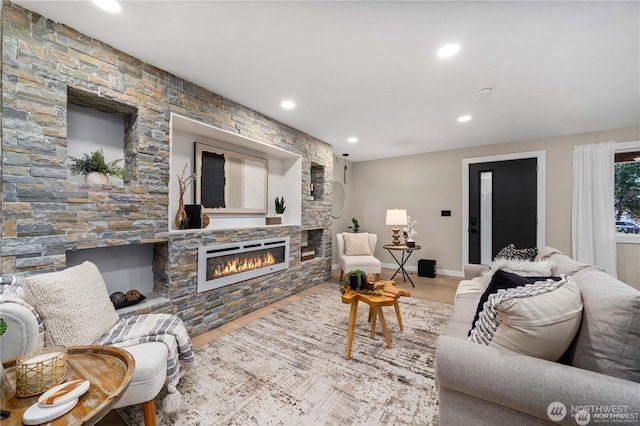 living room with a stone fireplace and wood-type flooring