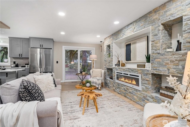 living room with light wood-type flooring and a stone fireplace