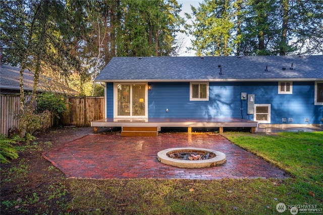 back of property featuring a deck, a patio, a fire pit, and a lawn