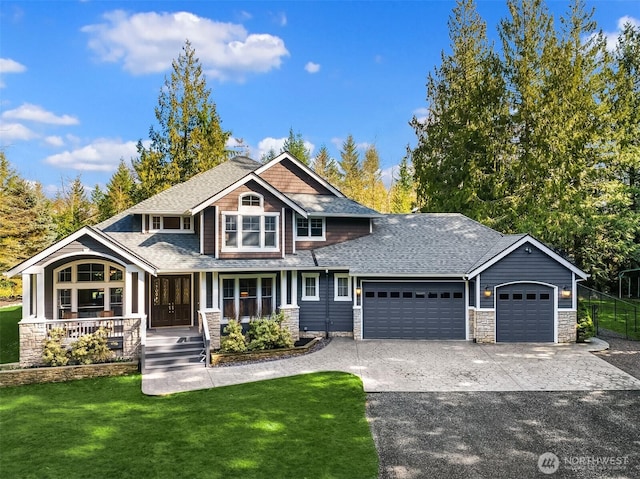 craftsman-style home with covered porch, a garage, driveway, roof with shingles, and a front yard