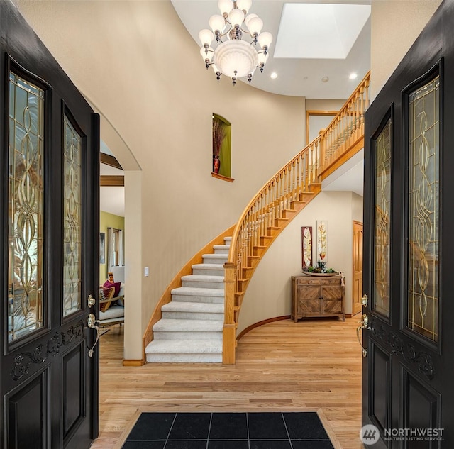 entrance foyer featuring stairs, a high ceiling, wood finished floors, and a notable chandelier