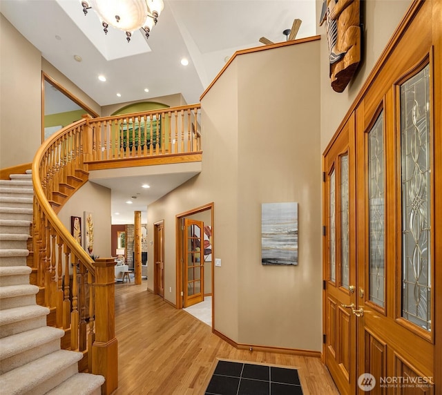 entrance foyer with a towering ceiling, light wood-style floors, stairs, and recessed lighting