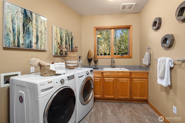 clothes washing area featuring washing machine and clothes dryer, cabinet space, a sink, and visible vents