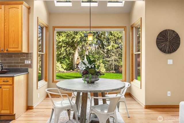 dining space with a skylight, light wood-style flooring, and a healthy amount of sunlight