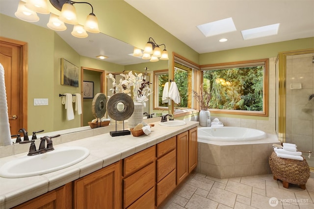 bathroom featuring a stall shower, a skylight, a sink, and a bath