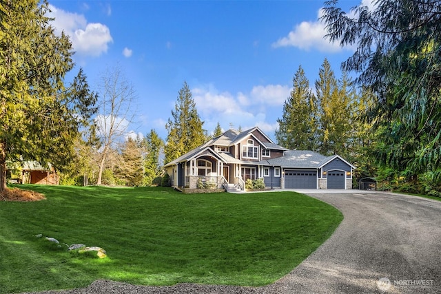 shingle-style home with a garage, a front yard, stone siding, and driveway