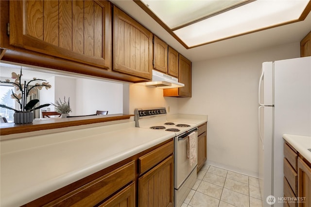 kitchen with white appliances, under cabinet range hood, light tile patterned floors, and light countertops