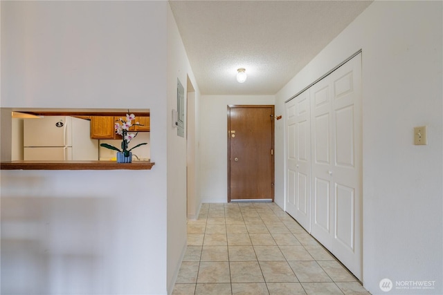 corridor featuring a textured ceiling and light tile patterned floors