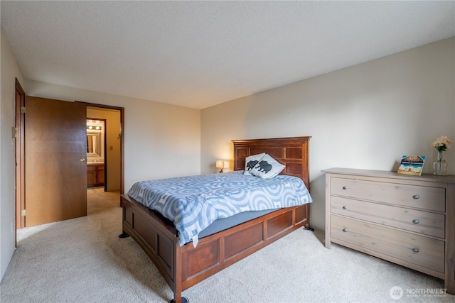 bedroom featuring ensuite bath, a textured ceiling, and light colored carpet