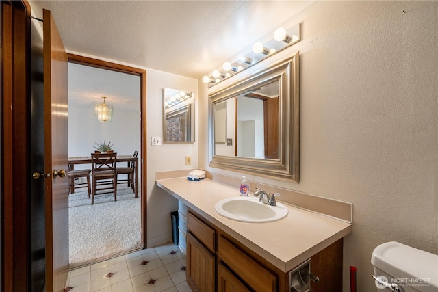 bathroom with a textured wall, vanity, toilet, and a textured ceiling