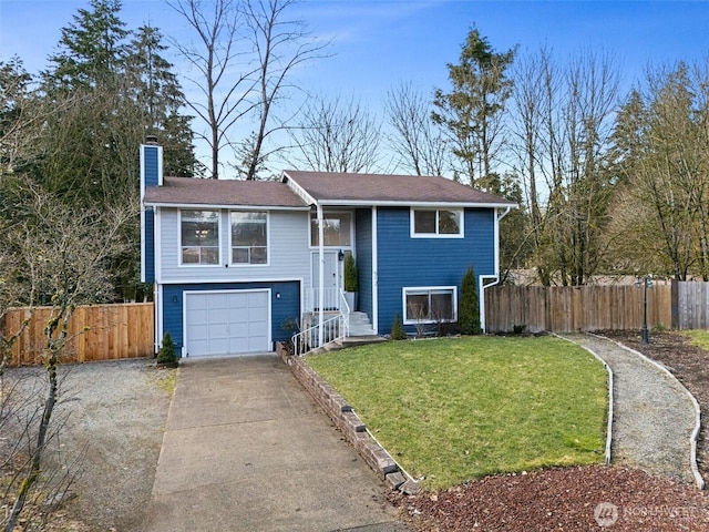 raised ranch with a garage, fence, concrete driveway, a chimney, and a front yard