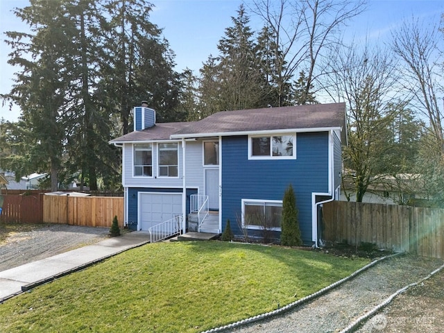 bi-level home featuring driveway, a chimney, a front yard, and fence