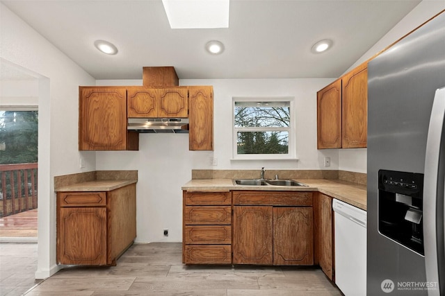 kitchen with light countertops, a sink, dishwasher, under cabinet range hood, and stainless steel fridge with ice dispenser