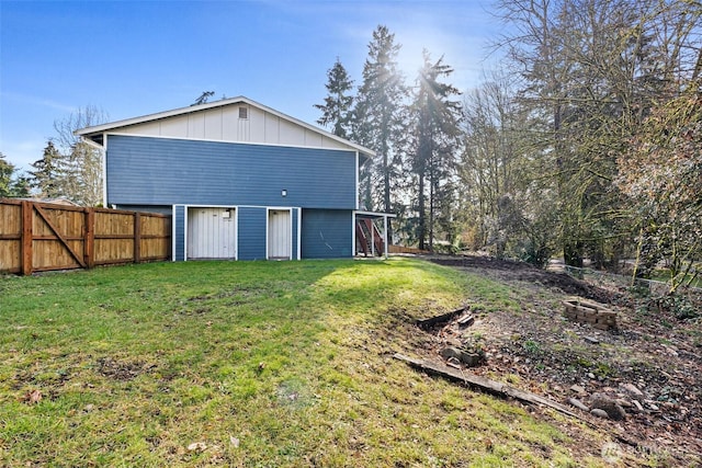 rear view of house with a fenced backyard, a lawn, and board and batten siding