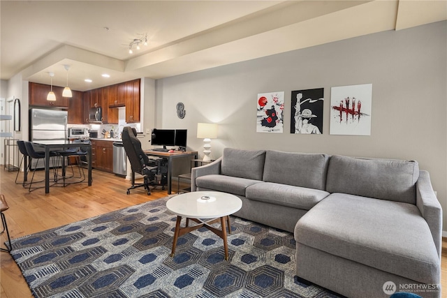 living area featuring light wood-style floors, rail lighting, and a toaster