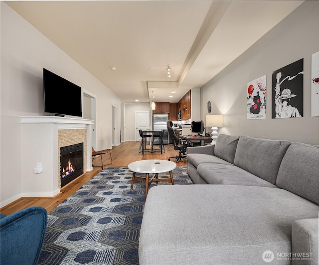 living area featuring a fireplace, wood finished floors, and baseboards