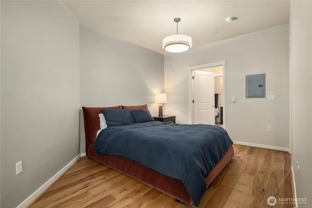 bedroom with light wood-style floors, electric panel, and baseboards