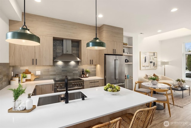 kitchen featuring light countertops, a kitchen breakfast bar, wall chimney exhaust hood, modern cabinets, and premium appliances