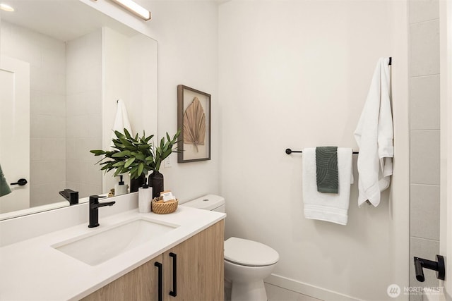 bathroom with baseboards, toilet, and vanity