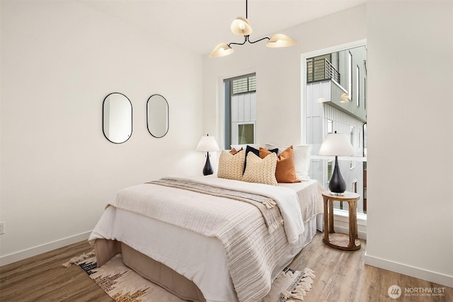 bedroom with baseboards, an inviting chandelier, and wood finished floors