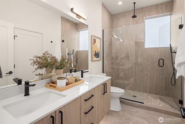 bathroom with double vanity, a stall shower, toilet, and a sink