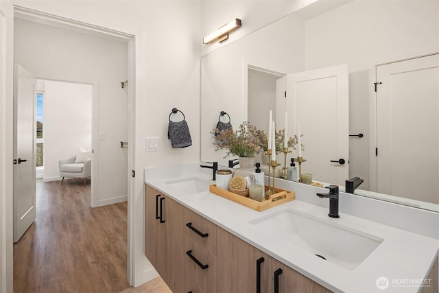 full bathroom with double vanity, wood finished floors, baseboards, and a sink