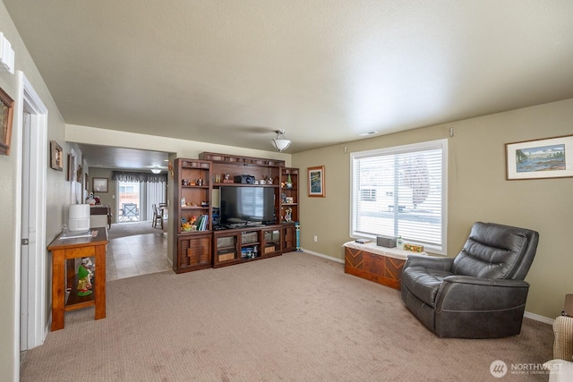 living area with visible vents, light carpet, and baseboards