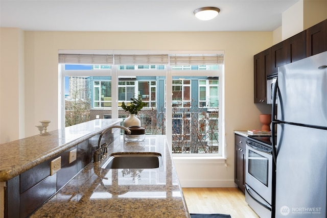 kitchen with a wealth of natural light, appliances with stainless steel finishes, dark brown cabinets, and a sink