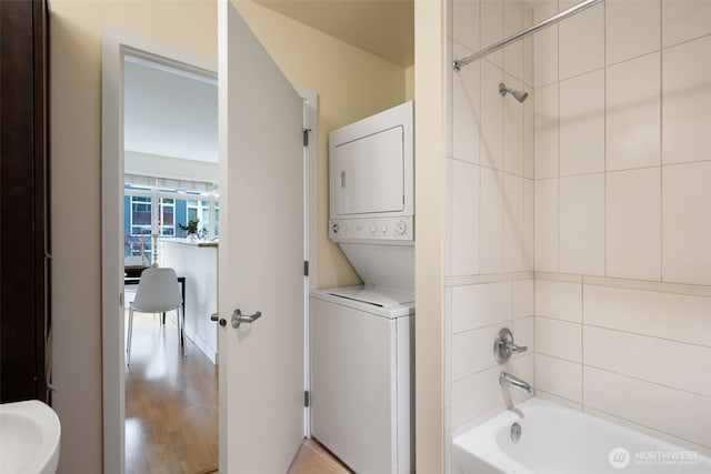 full bath featuring shower / washtub combination, stacked washer / drying machine, and wood finished floors