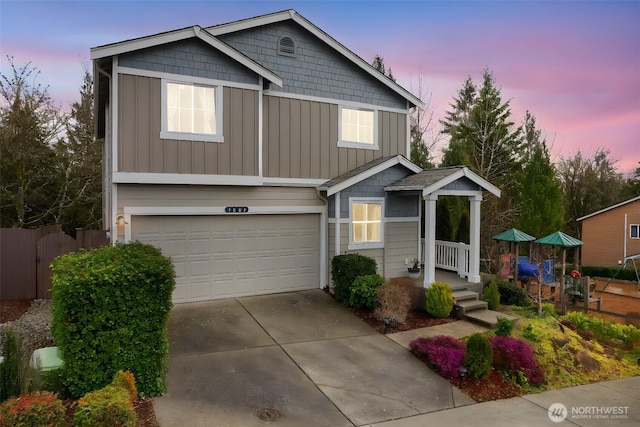 view of front facade with board and batten siding, concrete driveway, fence, and a garage