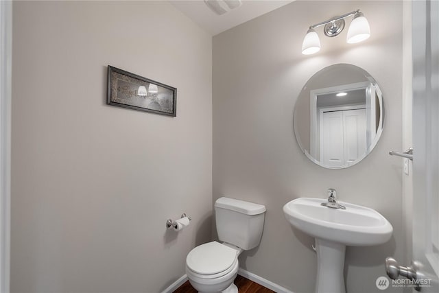 half bath featuring visible vents, toilet, and baseboards