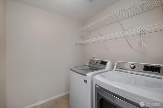 clothes washing area featuring laundry area, washer and clothes dryer, and baseboards