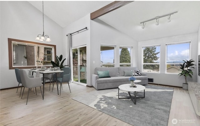 living room featuring plenty of natural light, light wood-type flooring, high vaulted ceiling, and an inviting chandelier