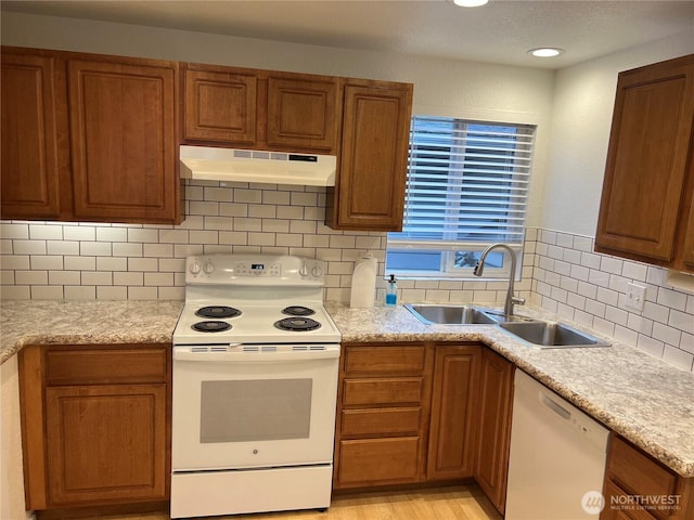 kitchen with white appliances, light hardwood / wood-style floors, sink, and backsplash