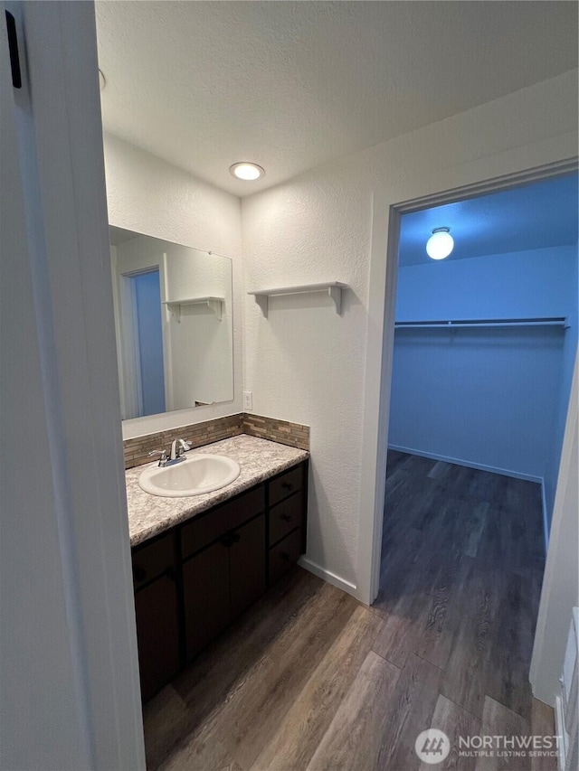 bathroom with a textured ceiling, vanity, and wood-type flooring