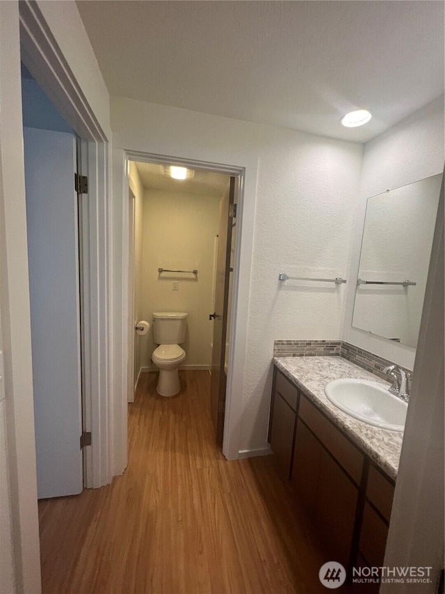 bathroom with vanity, toilet, and hardwood / wood-style floors