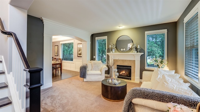 living area with arched walkways, a healthy amount of sunlight, carpet flooring, and a premium fireplace