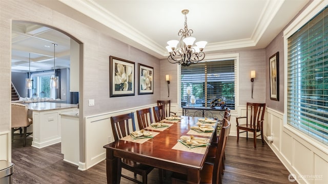 dining room featuring a wainscoted wall, dark wood-type flooring, ornamental molding, and a notable chandelier