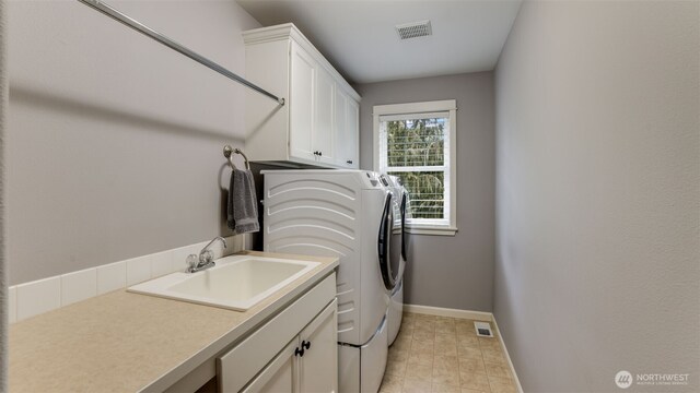 laundry room with visible vents, washing machine and dryer, a sink, and cabinet space