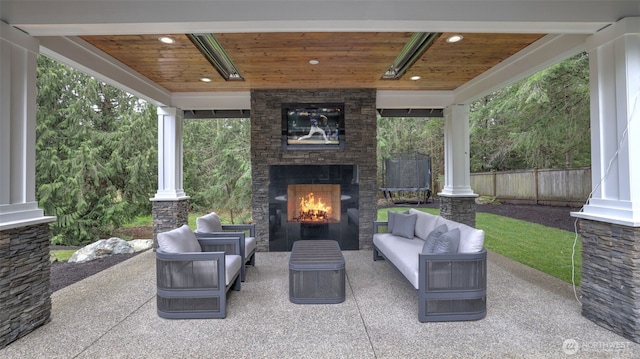 view of patio / terrace featuring an outdoor living space with a fireplace, a trampoline, and fence