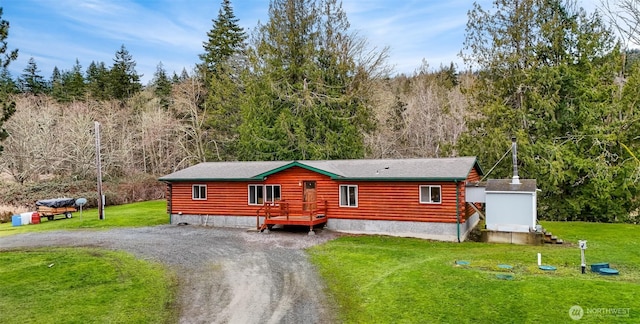 cabin with driveway, a front lawn, and a view of trees