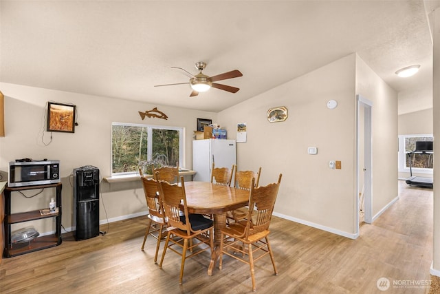 dining space featuring a ceiling fan, light wood-style flooring, and baseboards